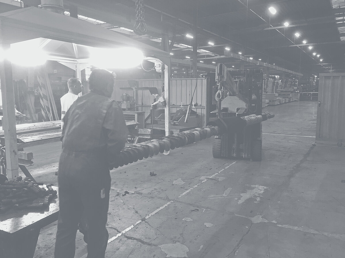 Gabelstapler transportiert Tragwellen mit Elementen durch eine Fabrikhalle.