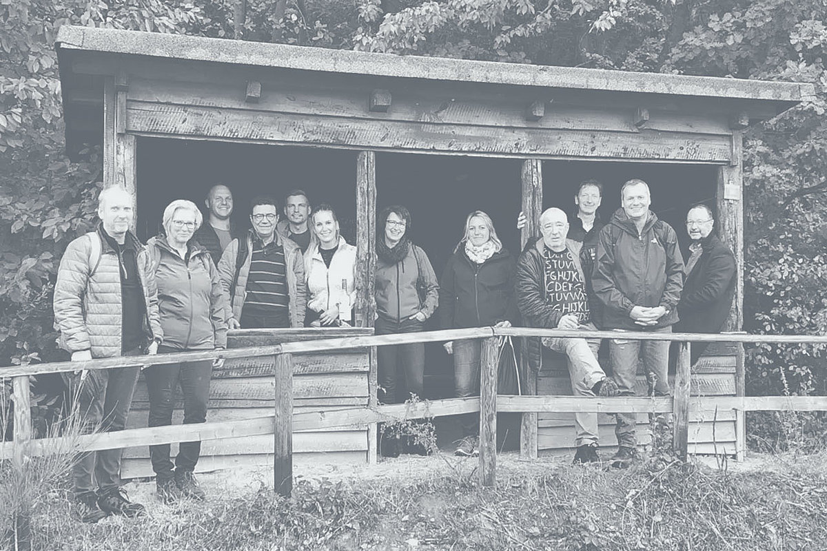 Group photo of the employees of Extruder Experts in front of a wooden hut