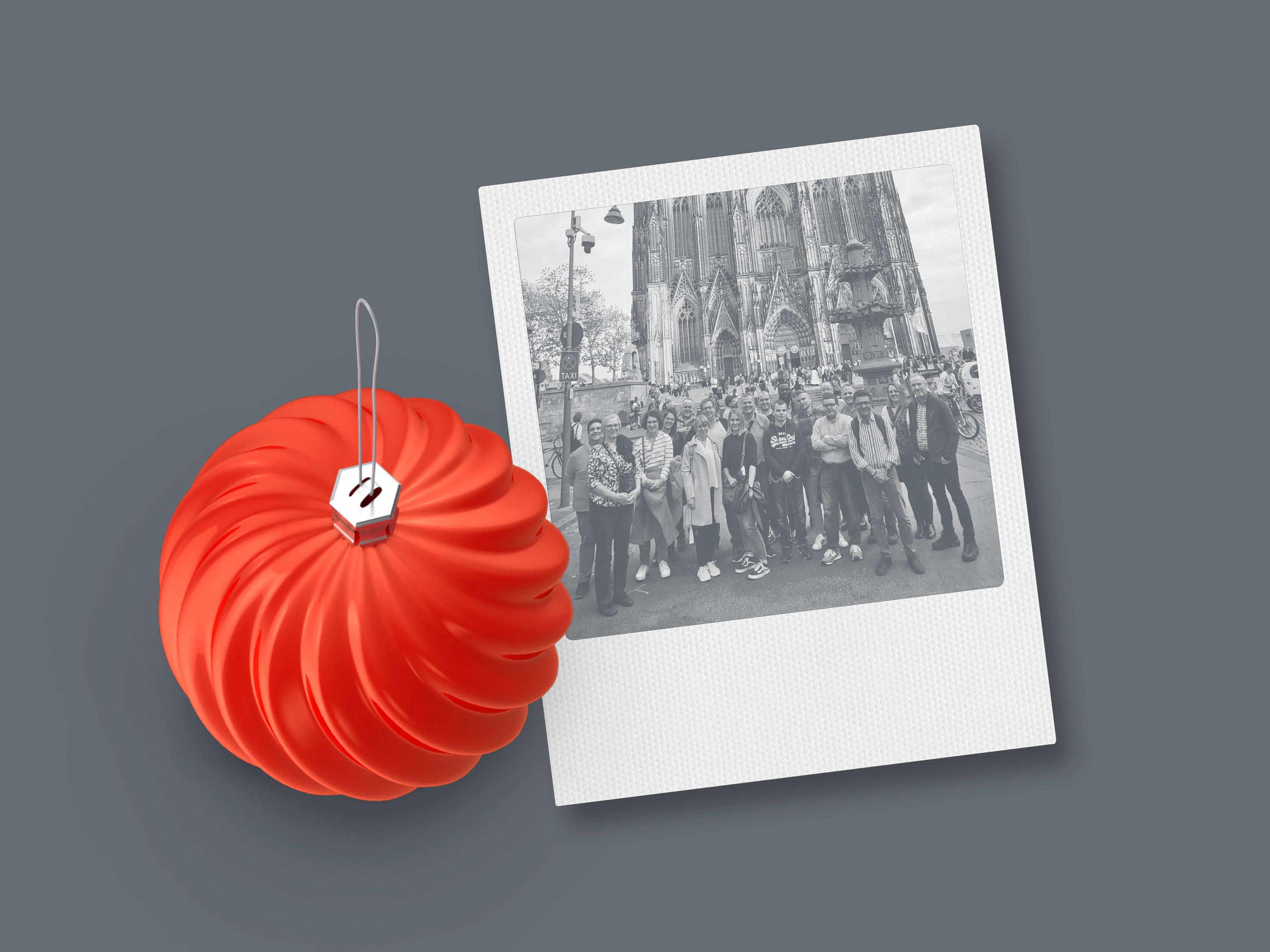 Boule de Noël en rouge avec Polaroid de la sortie d'équipe d'Extruder Experts à Cologne.