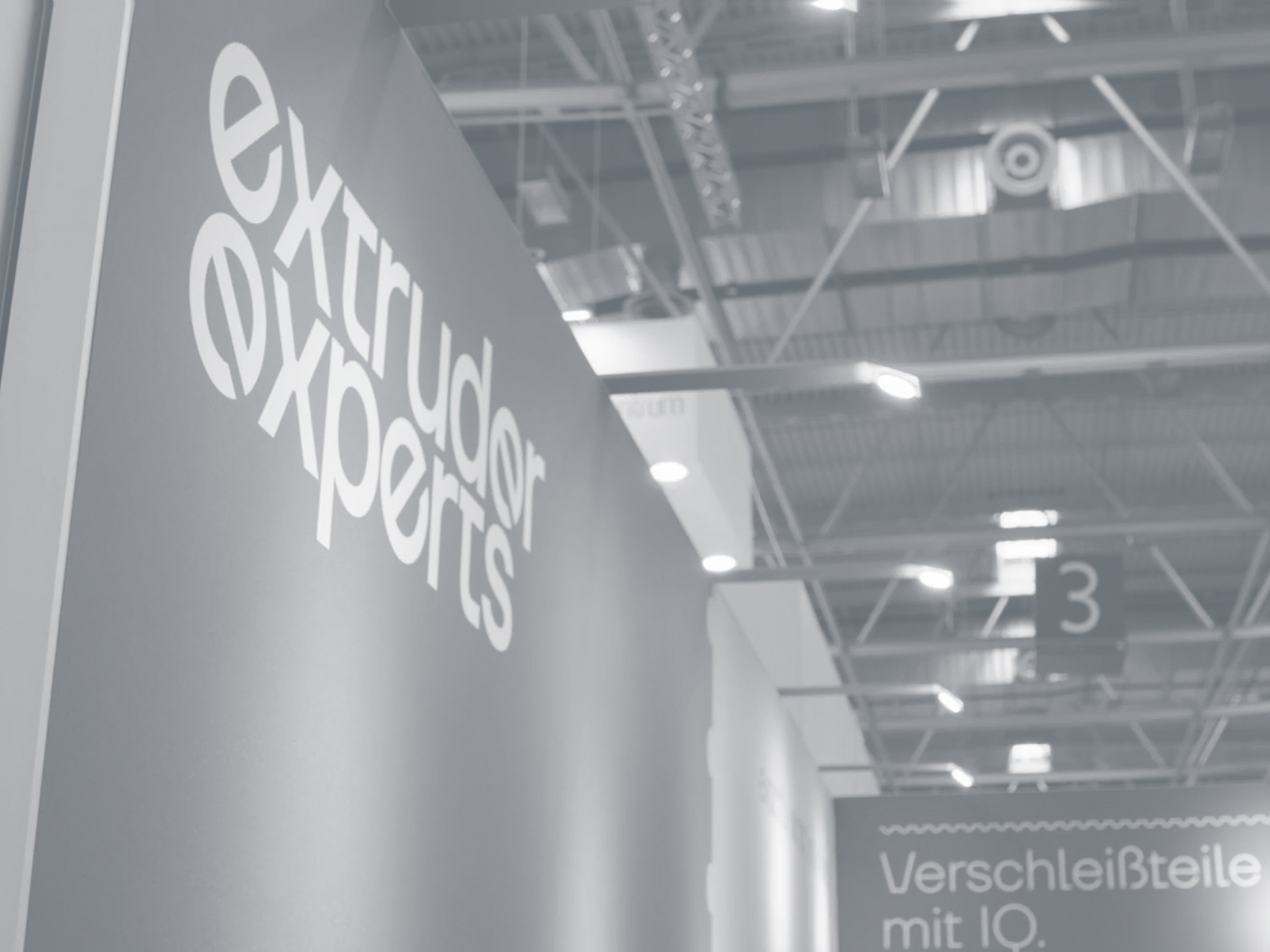Un mur d'exposition avec le logo d'Extruder Experts dans un hall d'exposition.